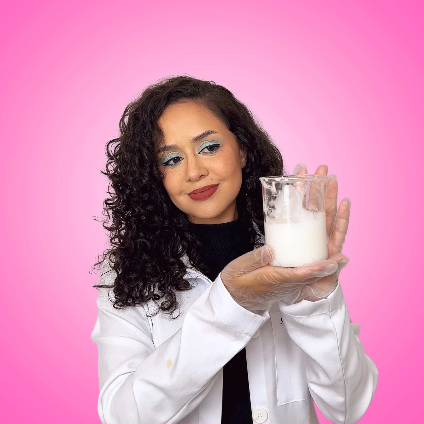 Alice Ferreira de jaleco segurando um béquer com creme